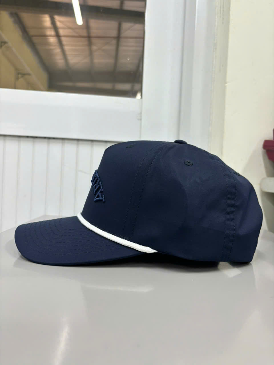 Side view of Injae Vina navy snapback golf cap with geometric logo embroidery