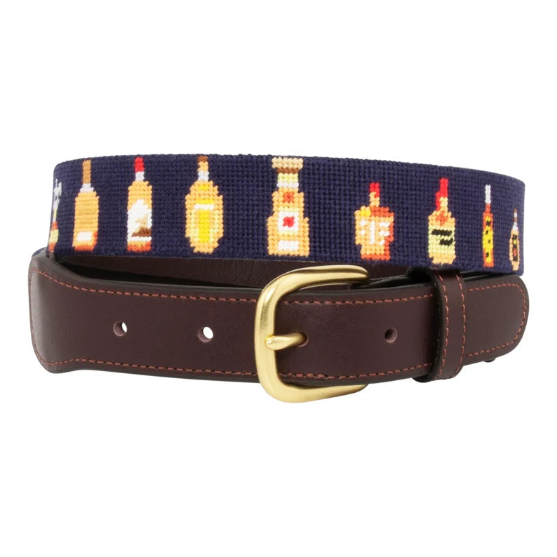 Whiskey bottles needlepoint belt close-up detail showing colorful spirit bottle pattern on navy blue