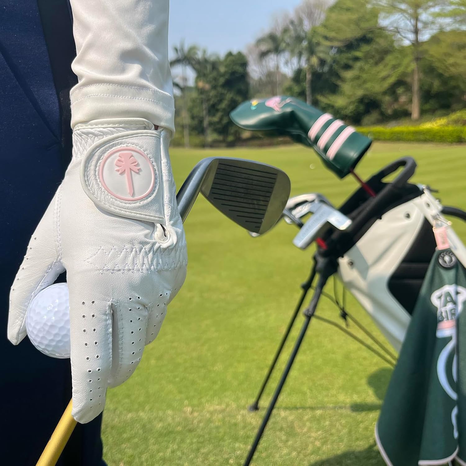 Women's cabretta sheepskin golf glove on course holding club with pink ball marker