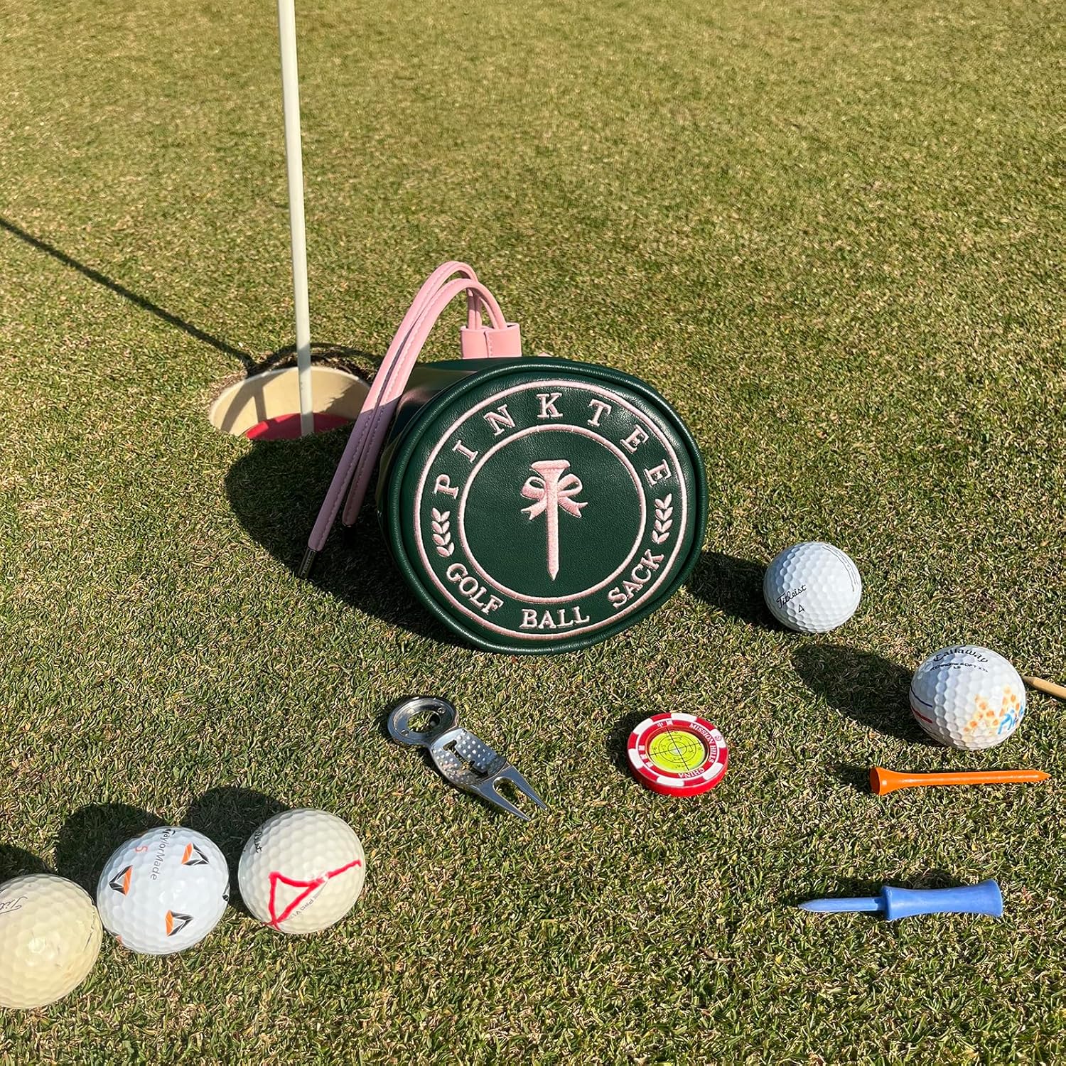 Pink Tee Golf Ball Sack dark green round pouch with pink handle on course